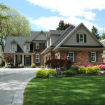 Red brick house with black shutters and pretty manicured lawn / garden